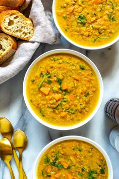 three bowls of soup with bread on the side