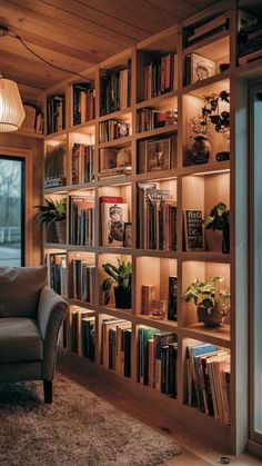 a living room filled with lots of books on top of a wooden shelf next to a window