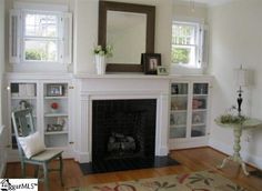 a living room filled with furniture and a fire place under a large mirror on top of a fireplace