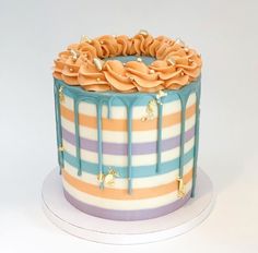 a multicolored striped cake with icing dripping from the top