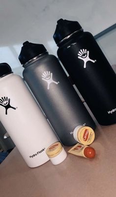 three water bottles sitting on top of a counter next to an orange and black bottle