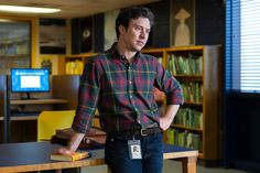 a man standing next to a table in a library