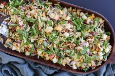 a wooden platter filled with salad on top of a blue cloth