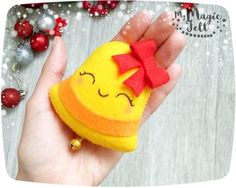 a hand holding a small felt toy with a red bow on it