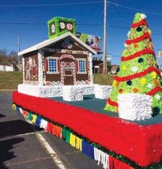 a large float with a christmas tree and house on it's side in a parking lot