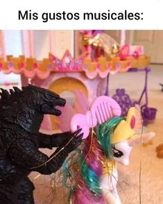 there is a toy godzilla next to a pony and a dragon on the floor in front of a doll house