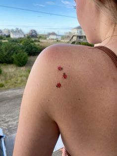 the back of a woman's shoulder with small red flowers on it