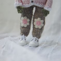 there is a knitted doll with flowers on it's leggings and shoes