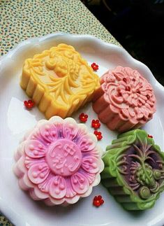 four cookies on a white plate with red and green decorations in the shape of flowers