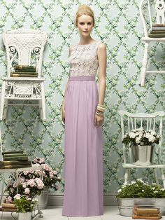 a woman standing in front of a wallpapered room with chairs and vases