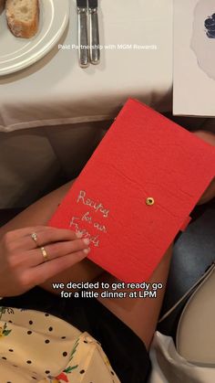 a woman holding a red book with writing on it