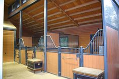 the inside of a horse barn with wooden stalls