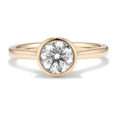 a yellow gold engagement ring with a round brilliant diamond in the center, on a white background