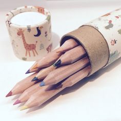 several pencils are sitting in a tube next to a cup