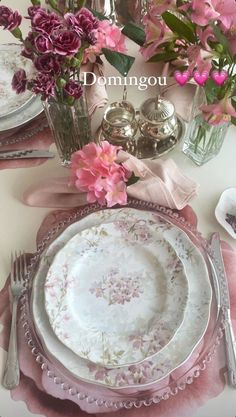 the table is set with pink flowers and silverware