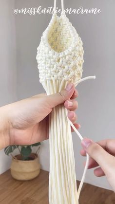 someone is holding an object made out of yarn and cotton string, with the thread being pulled through it