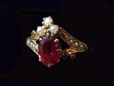 "A royal arrangement of garnet and seed pearls on this elegant Victorian ring.Three seed pearls crown the .40 oval faceted garnet.Two diagonal shoulder pieces with four inset seed pearls complement this gorgeous setting.Shorter, gold plumed braces balance out the design.Eight prongs hold the garnet and thirteen prongs hold the three pearls in place. Inside the ring band is inscribed,\"G. to A.\" in Victorian script. What a romance this must have been! Ring size: 7 US, N 1/2 UK, 14 Japan, China, Elegant Garnet Oval Cabochon Jewelry, Elegant Jewelry With Oval Cabochon Garnet, Victorian Oval Pearl Ring With Gemstone, Elegant Oval Cabochon Ruby Ring For Wedding, Oval Pearl Ring With Rose Cut Diamonds, Wedding Garnet Cabochon Jewelry, Victorian Wedding Jewelry With Gemstone Accents, Elegant Oval Ruby Ring With Rose Cut Diamonds, Elegant Multi-stone Ruby Ring