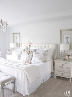 a white bed sitting in a bedroom next to a chandelier