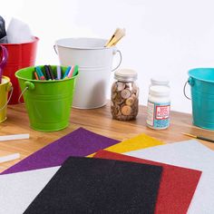 several buckets and other craft supplies sitting on a wooden floor next to each other