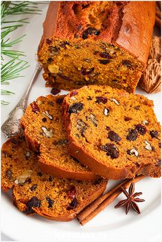 slices of pumpkin bread with raisins and anise on a white plate next to cinnamon sticks