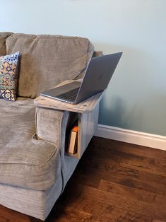 a couch with a laptop sitting on it's side table next to a wall