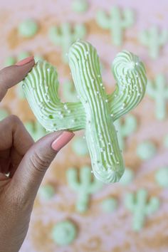 a person holding up a fake cactus shaped cookie