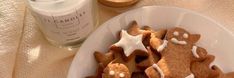 some cookies are on a white plate and next to a jar of icing sugar