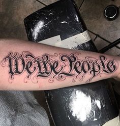 a person with a tattoo on their arm that says we the people in cursive writing