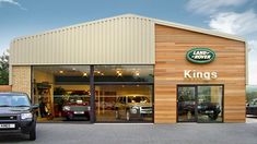 a car dealership with cars parked in front of the doors and two trucks outside