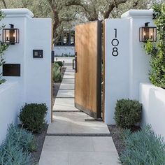 an entrance to a house with two wooden doors and plants growing on the side of it