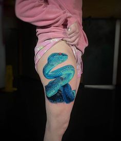 a woman's thigh with a blue snake tattoo on her leg and the bottom part of her thighs