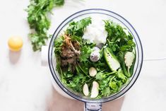 a blender filled with green vegetables on top of a table