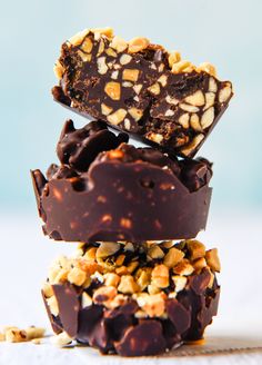 three pieces of chocolate and nuts stacked on top of each other in front of a blue background