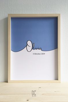 a wooden frame holding a blue and white print with the name olna on it