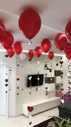 red and white balloons are hanging from the ceiling in a room decorated with heart - shaped confetti