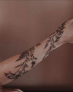 a woman's arm with flowers and leaves tattooed on the left side of her arm