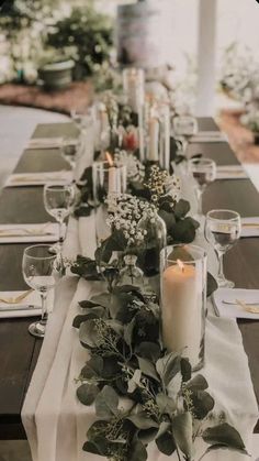 a long table is set with candles and greenery for an elegant dinner or party