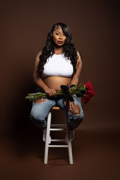 a woman sitting on a stool with flowers in her lap and holding roses behind her back