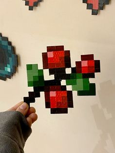 a person holding a piece of art made out of legos on a white wall