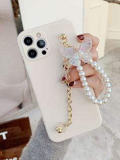 a woman is holding up her phone case with pearls and a butterfly attached to it