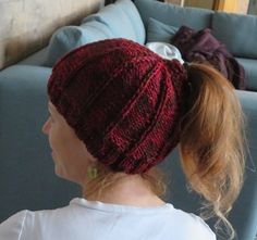 a woman sitting on a couch wearing a knitted hat