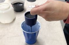 a person is pouring something into a blue cup