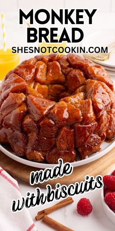 a monkey bread on a white plate with raspberries and orange juice in the background