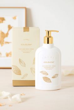 a bottle of gold leaf hand lotion next to a cardboard box on a table