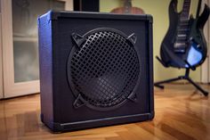 a guitar amplifier sitting on top of a hard wood floor next to an electric guitar