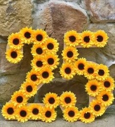 the letters are made out of sunflowers and placed on top of a stone wall