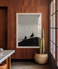 a room with wood paneling and a painting on the wall next to a potted plant