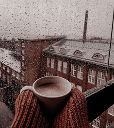 a cup of coffee sitting on top of a window sill next to a building