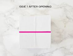 a white box with pink ribbon on it sitting on top of a marble countertop