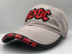 "This OSFM unstructured hat has the recognizable AC/DC logo! What makes this hat unique is the Amazing BRIMMTRIMM Hat Accessory that can be customized with any song/album/phrase. The BRIMMTRIMM is available in Red/White/Black/Gray/Pink color options. Hat options include Classic White/Black/Khaki/Charcoal/Pink/Gray/Red. Choose your BRIMMTRIMM and HAT choices in the dropdowns. Combine any of our Hat and BRIMMTRIMM color options We will confirm your customization choices before production. If you w Adjustable Baseball Cap For Fan Merchandise, Adjustable Fitted Hat With Curved Brim For Fans, Adjustable Curved Brim Fitted Hat For Fans, Curved Brim Fitted Hat For Fan Merchandise, Adjustable Flat Brim Hats For Fans, Ac Dc Logo, Acdc Logo, Ac Dc Band, Dc Logo